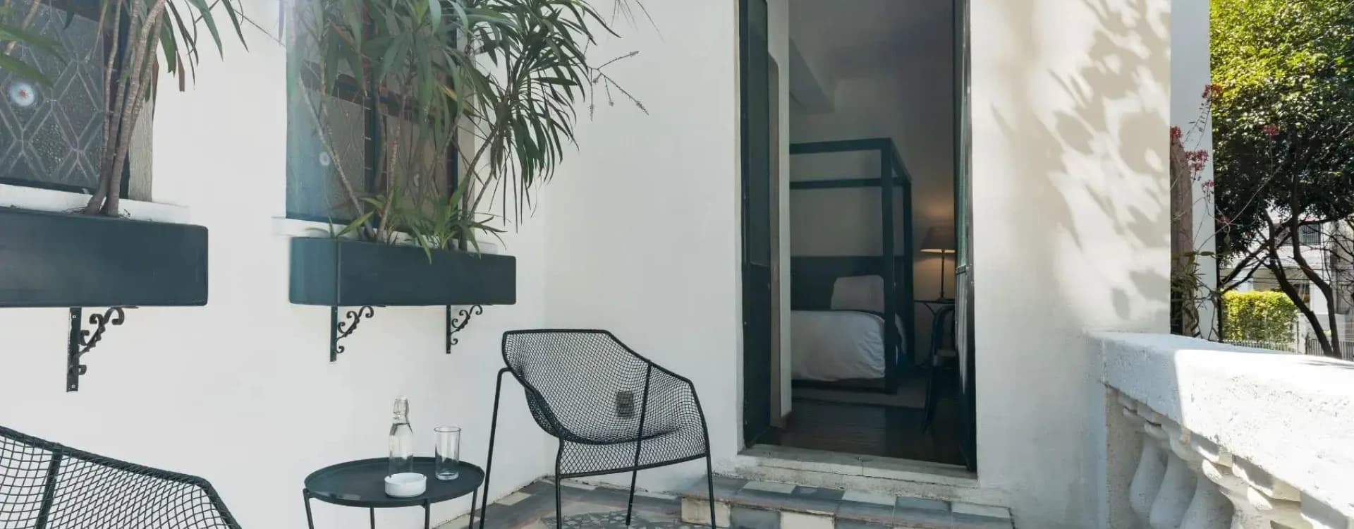 Courtyard with an arched door and a mesh chair; beyond it, a four-poster bed