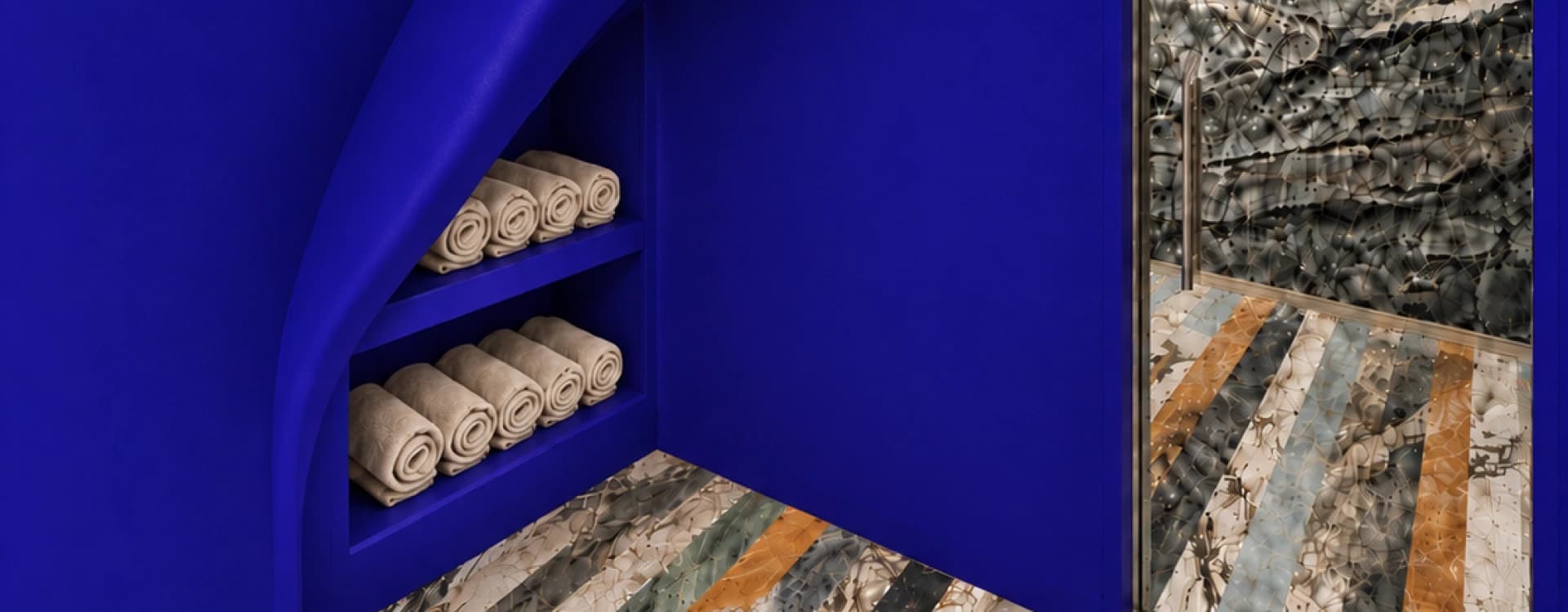 A cobalt-blue niche with rolled towels on curved shelves, beside the entrance to a shower with a striped marble floor