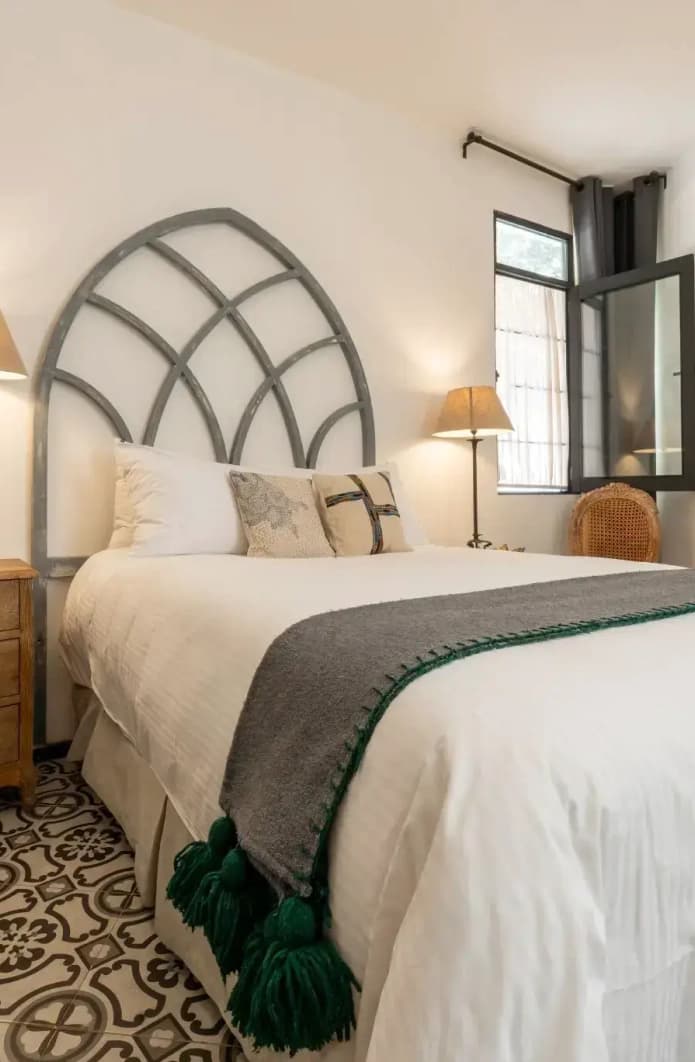 Bed with an arched cut-out headboard, a timber nightstand and a talavera mosaic floor