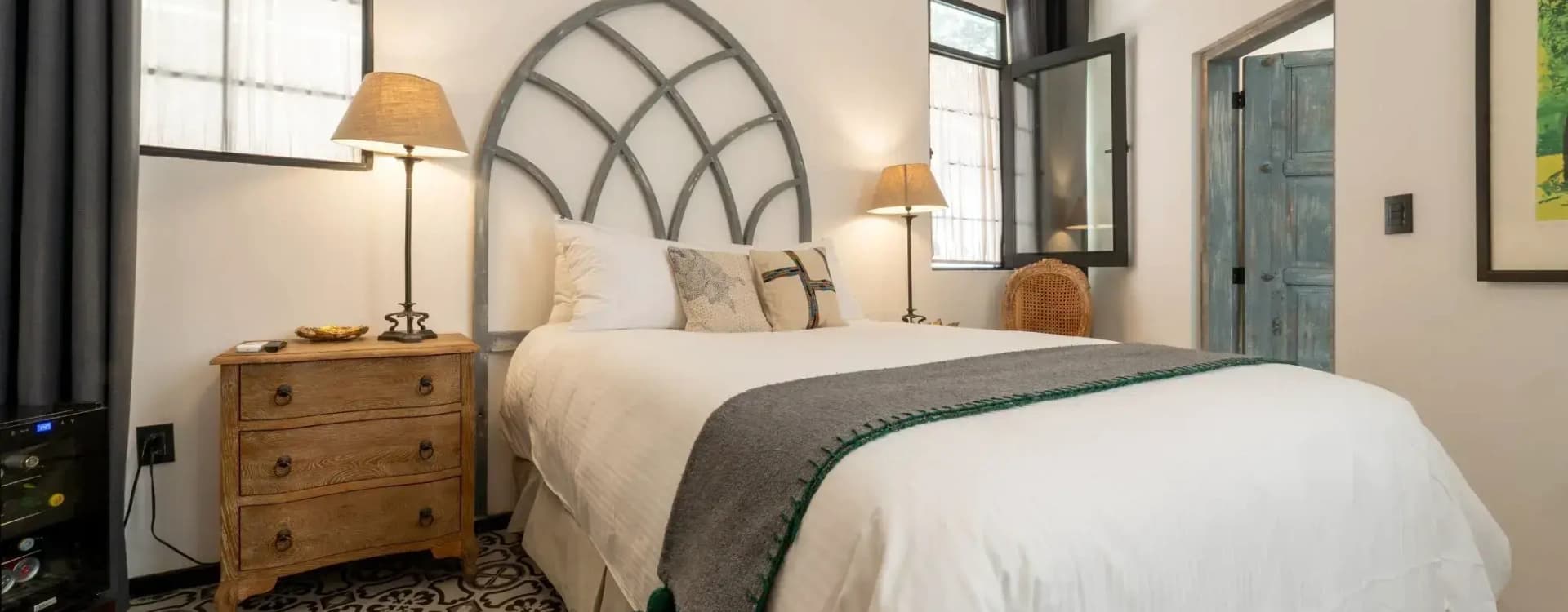 Bed with an arched cut-out headboard, a timber nightstand and a talavera mosaic floor