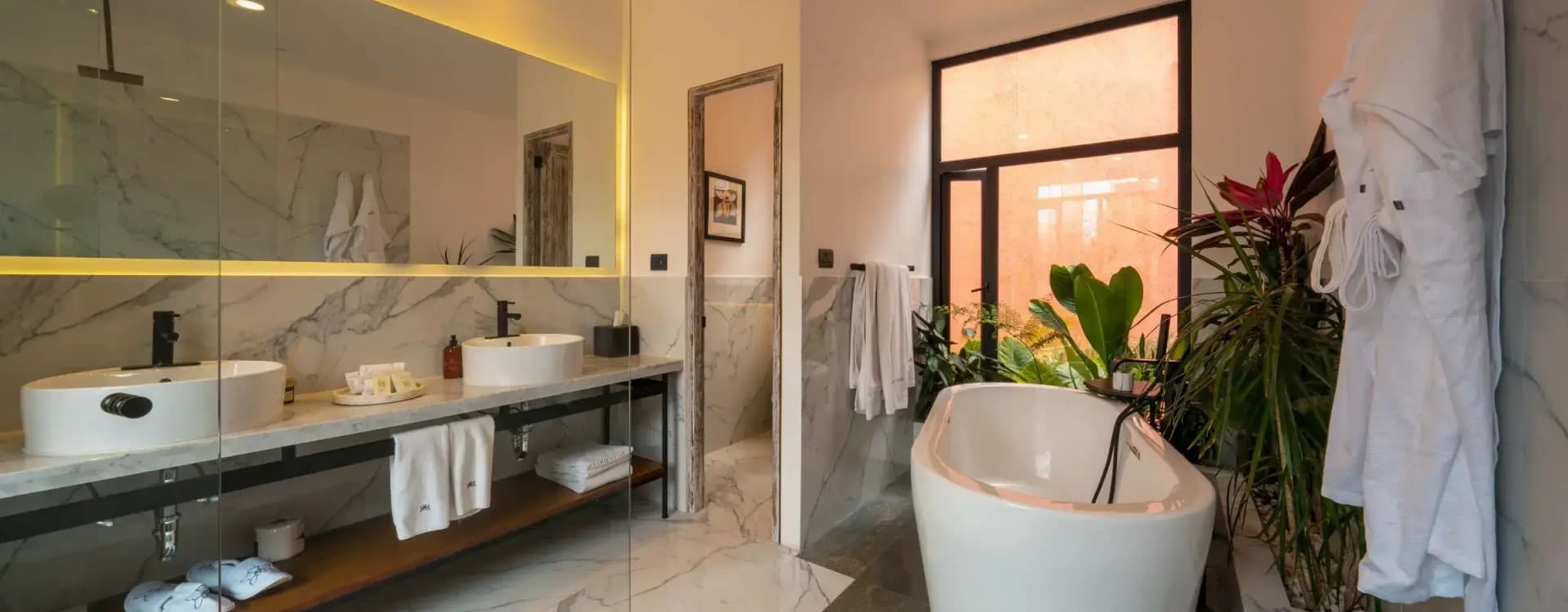 Bathroom with a freestanding tub, a marble vanity and a window onto the garden