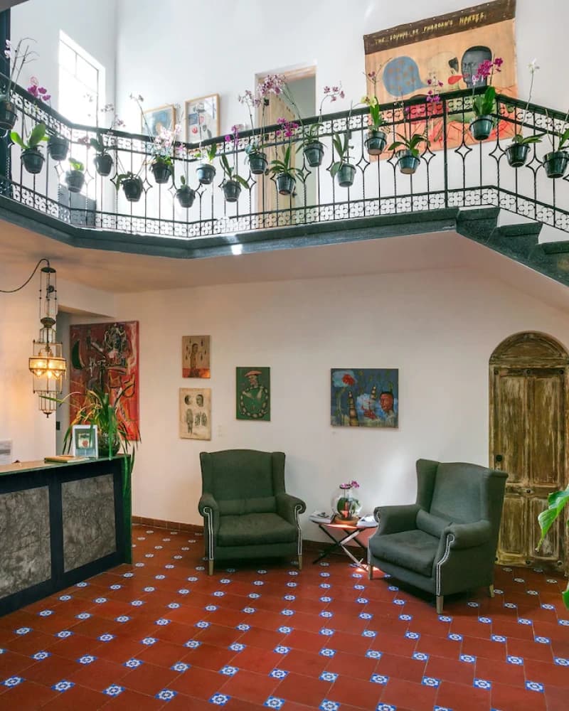The lobby: the marble reception desk, the staircase with hanging orchids, reading chairs and red-and-blue tiled floor